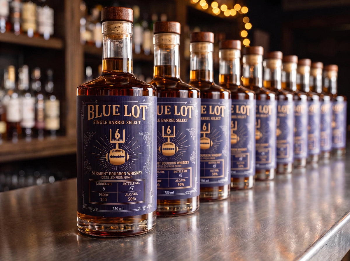 A row of Blue Lot Single Barrels Select bourbon whiskey bottles lined up on a polished bar counter in a dimly lit bar setting.